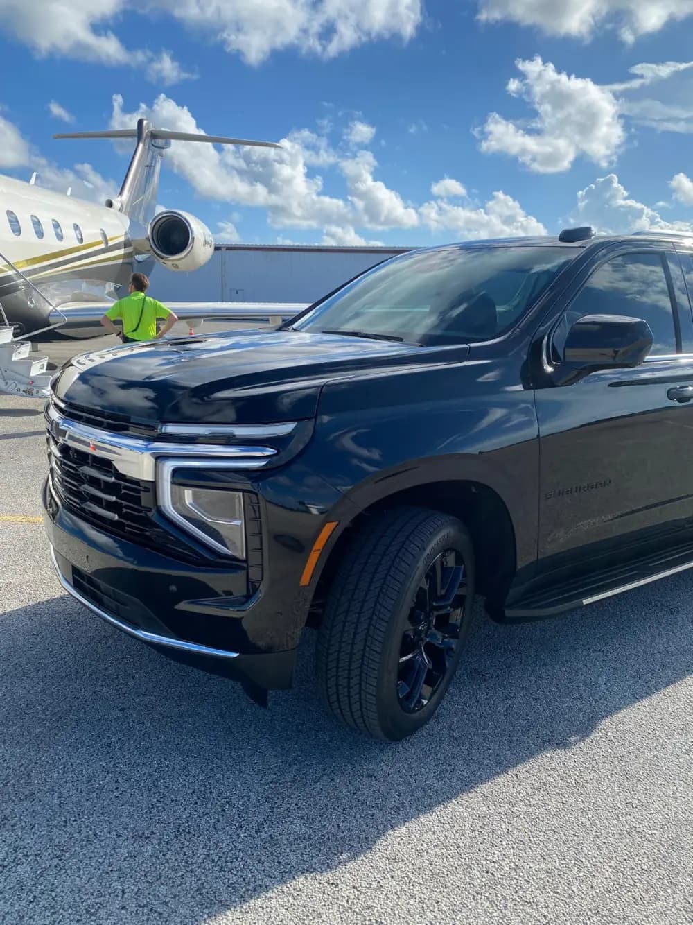 Our black Chevrolet Suburban beside a private jet on the airport apron